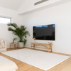 Modern living room with a large TV, plant, and wooden bench.