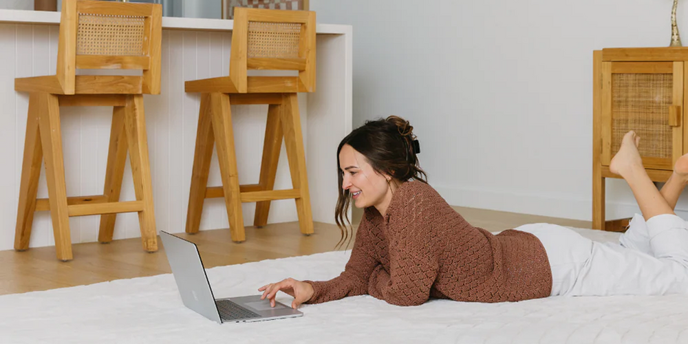 woman on a laptop laying on a white rug