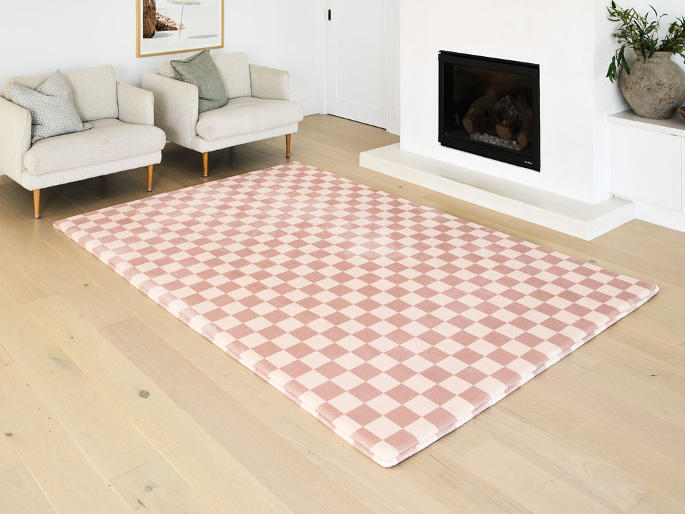Pink checkered rug on a wooden floor in a living room setting.