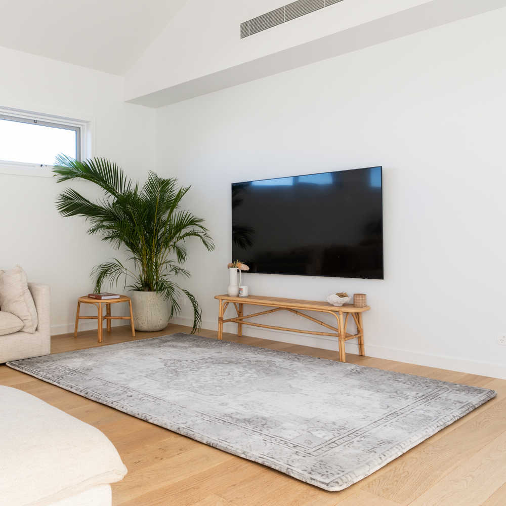Modern living room with a large TV, rug, and plants. Relax Mat