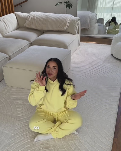 woman in yellow outfit, talking about the mat she is sitting on.